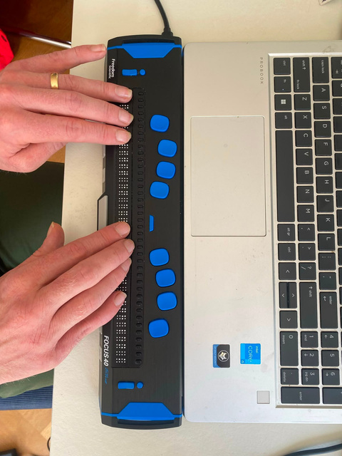 Testpanellid bedient een brailleleesregel die aan een laptop gekoppeld is