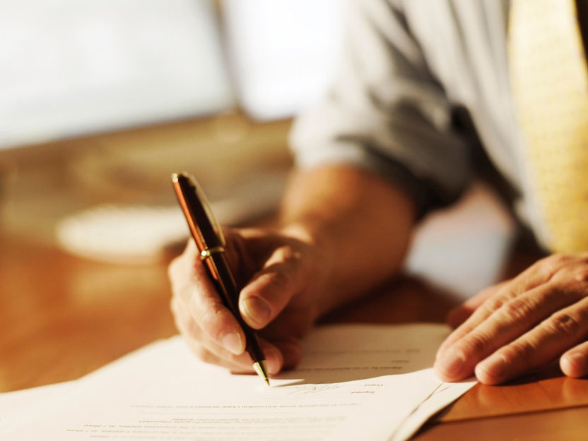 Close-up van een hand die met een pen een document ondertekent